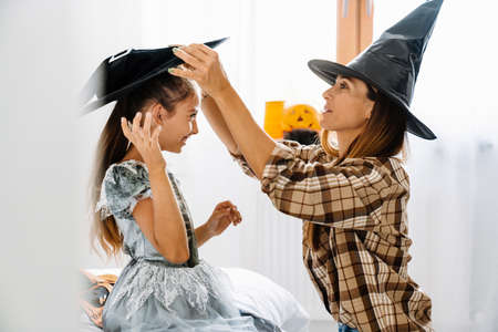 White mother and daughter smiling while getting ready for Halloween at homeの写真素材
