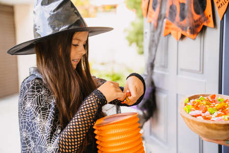 White girl wearing witch costume trick-or-treating during Halloween outdoorsの写真素材