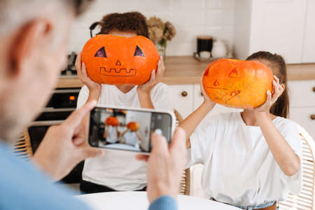 White man taking photo of his children while getting ready for Halloween at homeの写真素材