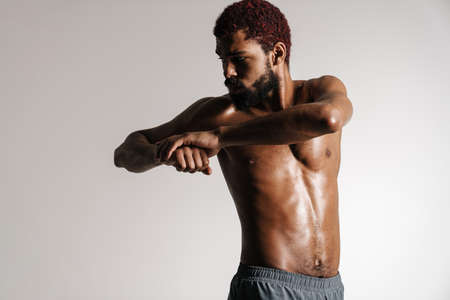 Black shirtless sportsman doing exercise while working out isolated over white backgroundの写真素材