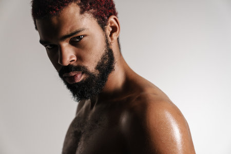 Black shirtless bearded man posing and looking at camera isolated over white backgroundの写真素材