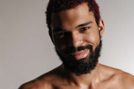 Black shirtless bearded man smiling and looking at camera isolated over white backgroundの写真素材
