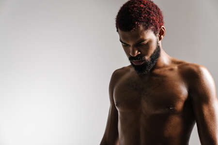 Black shirtless bearded man posing and looking downward isolated over white backgroundの写真素材