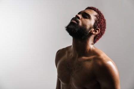 Black shirtless sportsman posing on camera with eyes closed isolated over white backgroundの写真素材