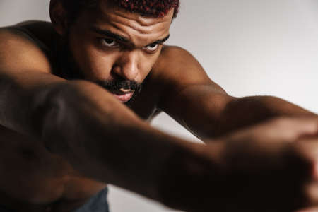 Black shirtless sportsman doing exercise while working out isolated over white backgroundの写真素材