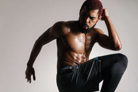 Black shirtless sportsman doing exercise while working out isolated over white backgroundの写真素材