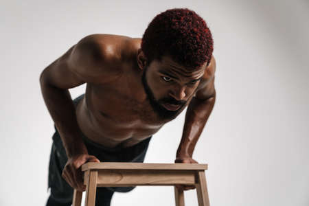 Black shirtless sportsman doing push-ups while working out isolated over white backgroundの写真素材