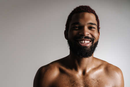 Black shirtless bearded man smiling and looking at camera isolated over white backgroundの写真素材