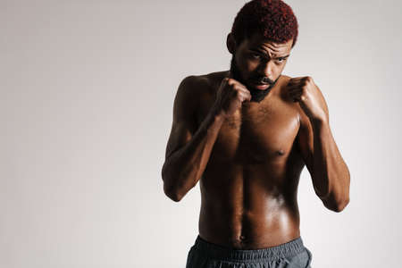 Black shirtless bearded sportsman posing with clenched fists isolated over white backgroundの写真素材