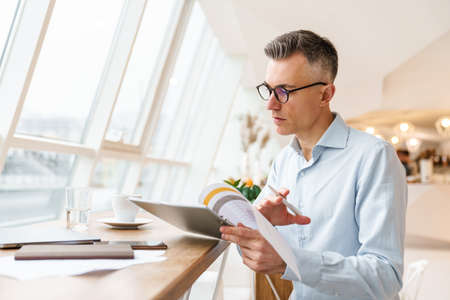 Handsome man working with documents in cafe indoorsの写真素材