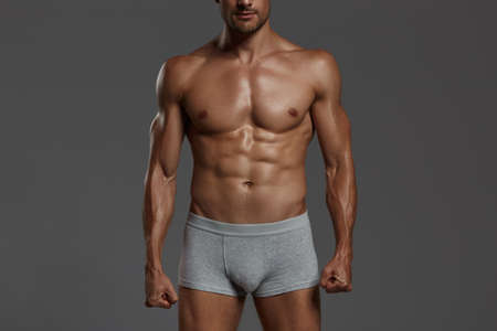 Naked sportive torso of sexual european athletic man. Front view of man wear underpants. Isolated on dark gray background. Studio shoot. Copy spaceの写真素材