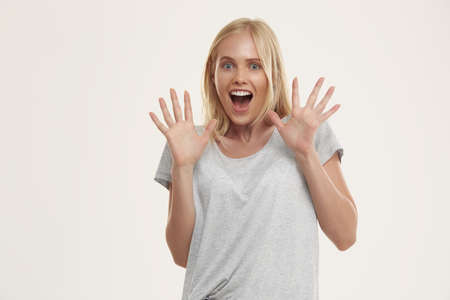 Young surprised european girl with open mouth. Beautiful blonde female teenager with blue eyes wear...