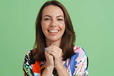 Young european woman laughing and looking at camera isolated over green background