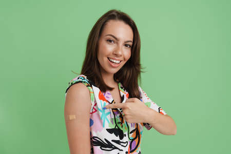Young european woman smiling and pointing finger at her bandage isolated over green background