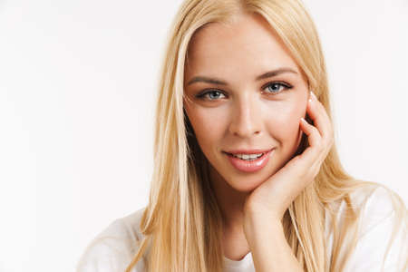 Young blonde woman in t-shirt smiling and looking at camera isolated over white backgroundの写真素材