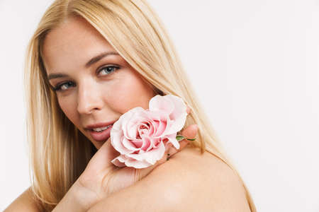 Half-naked young blonde woman posing with pink rose isolated over white backgroundの写真素材