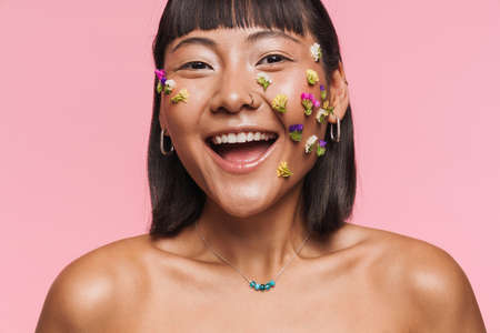 Beauty portrait of a smiling happy young brunette asian woman with makeup facial decoration over wall backgroundの写真素材