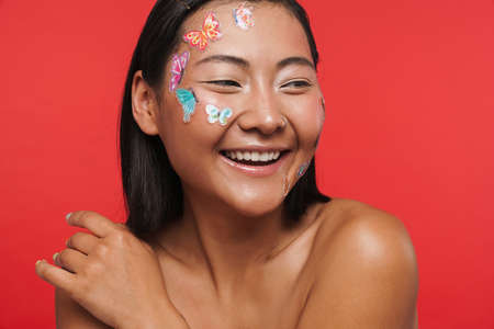 Beauty portrait of a smiling happy young brunette asian woman with makeup facial decoration posing...