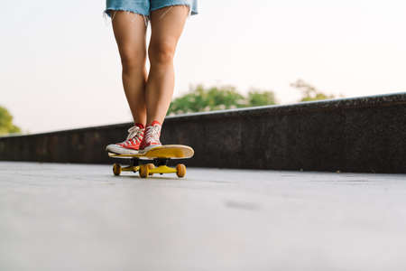 Cropped image of a young woman riding on a skateboard in the green parkの写真素材