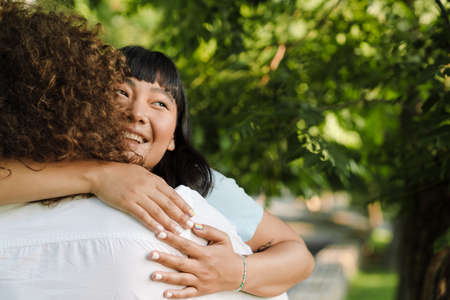 Happy young multiethnic couple cuddling embracing together in the green park close upの写真素材