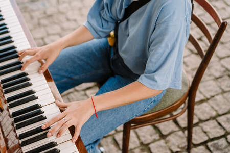 Young woman playing piano while sitting on chair outdoorsの写真素材