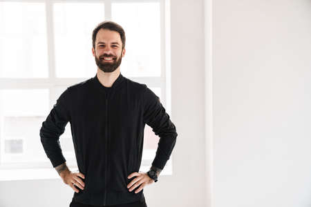 Smiling young brunette white man in sportswear standing indoors