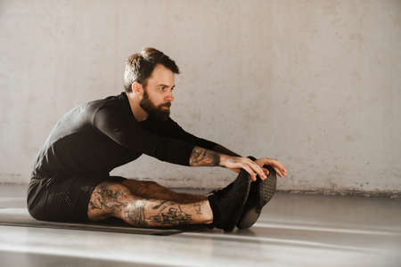 Confident mid aged white sportsman exercising in a bright room stretchingの写真素材