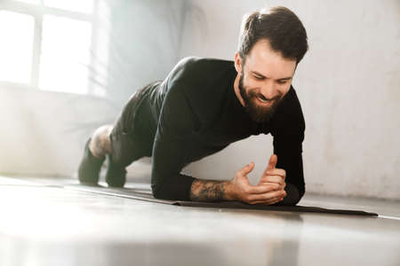 Smiling mid aged white sportsman exercising in a bright room doing plankの写真素材