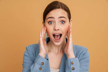 Young ginger excited woman expressing surprise at camera isolated over yellow backgroundの写真素材
