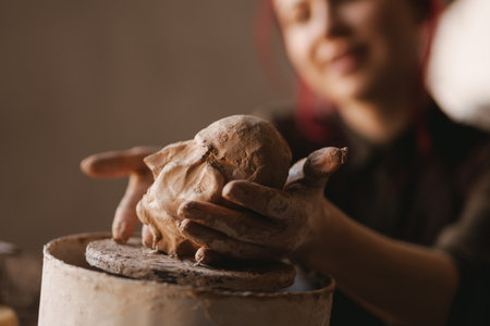 Young smiling woman sculptor artist creating a bust sculpture with clay in an art studioの写真素材