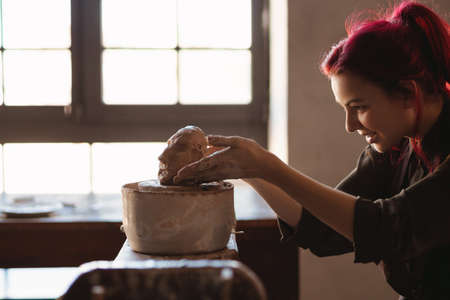 Young woman sculptor artist creating a bust sculpture with clay in an art studio close upの写真素材