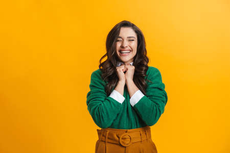 Portrait of a happy smiling casual woman standing over yellow background rejoycingの写真素材