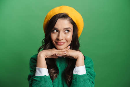 Young brunette woman laughing and looking aside isolated over green backgroundの写真素材