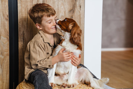 Happy little kid playing with his dog at home on a floorの写真素材