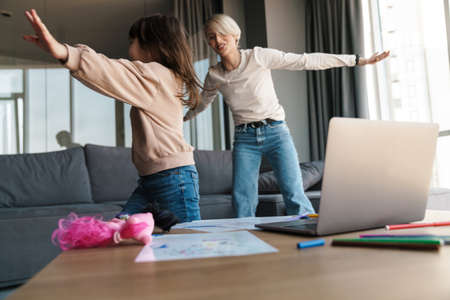 Happy mother and preschooller daughter playing having fun together in the living room