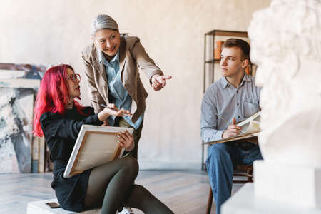 Mature teacher talking with her students during class in art school indoors