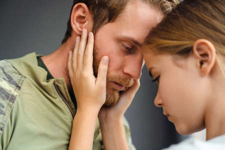 Sad girl hugging her father while standing head to head indoorsの写真素材