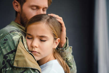 Masculine sad military man hugging her upset daughter indoorsの写真素材