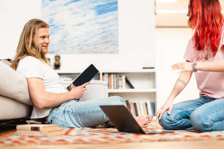 White man and woman talking and laughing while sitting on floor at homeの写真素材