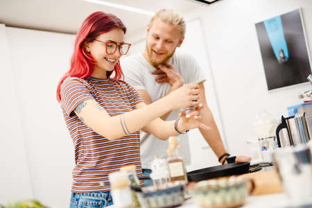 Young white couple smiling while cooking together in kitchen at home