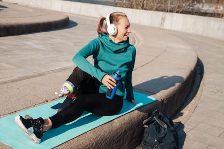 Young sportswoman with prosthesis drinking water while working out outdoorsの写真素材