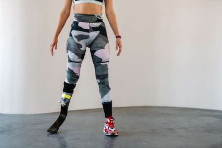Young sportswoman with prosthesis working out indoors