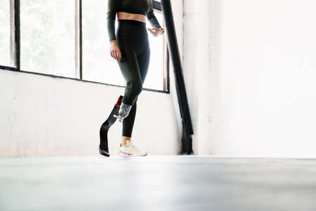 Young woman with prosthesis standing while working out indoors