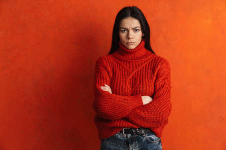 Young hispanic woman posing and looking at camera isolated over orange wallの写真素材