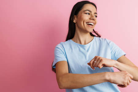 Brunette hispanic woman singing and dancing at camera isolated over pink wallの写真素材