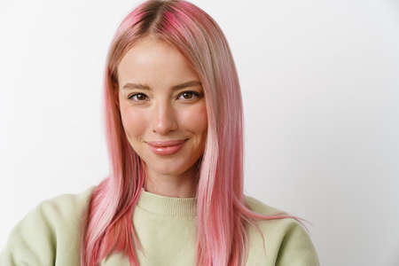 Young white woman with pink hair smiling and looking at camera isolated over white backgroundの写真素材