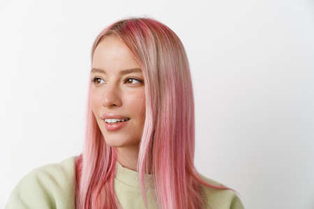 Young white woman with pink hair smiling and looking aside isolated over white background