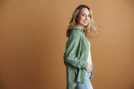 Happy beautiful woman smiling and looking at camera isolated over beige wall