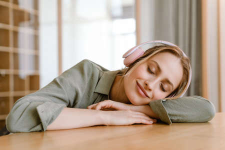 Young woman smiling while listening music headphones at homeの写真素材