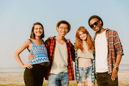 Young multiracial friends hugging and smiling together while posing outdoorsの写真素材